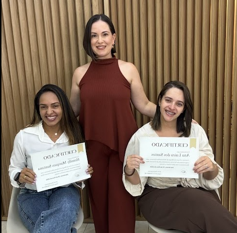 Aline De Cressenzo entre duas alunas segurando certificados de conclusão